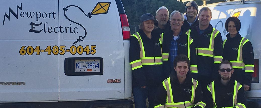 Newport Electric team standing with their original branded vans